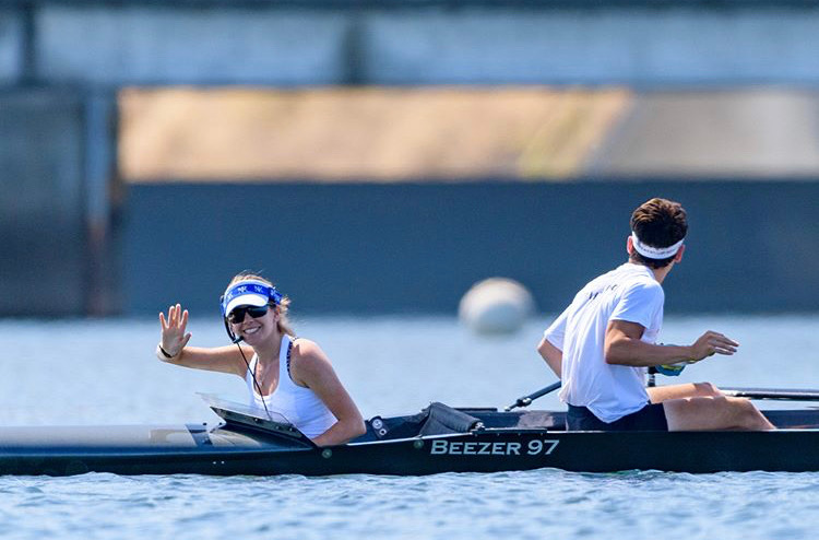 Emily Mahaffy (left) waves to the camera while rowing by. 