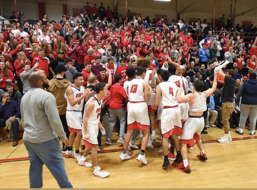CHE boys basketball team celebrate in front of a large crowd after a win. 
