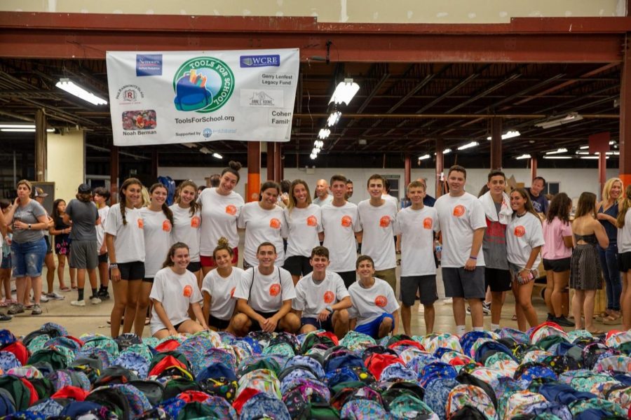 Volunteers+gather+in+front+of+the+backpacks+that+were+packed+during+last+years+event.+