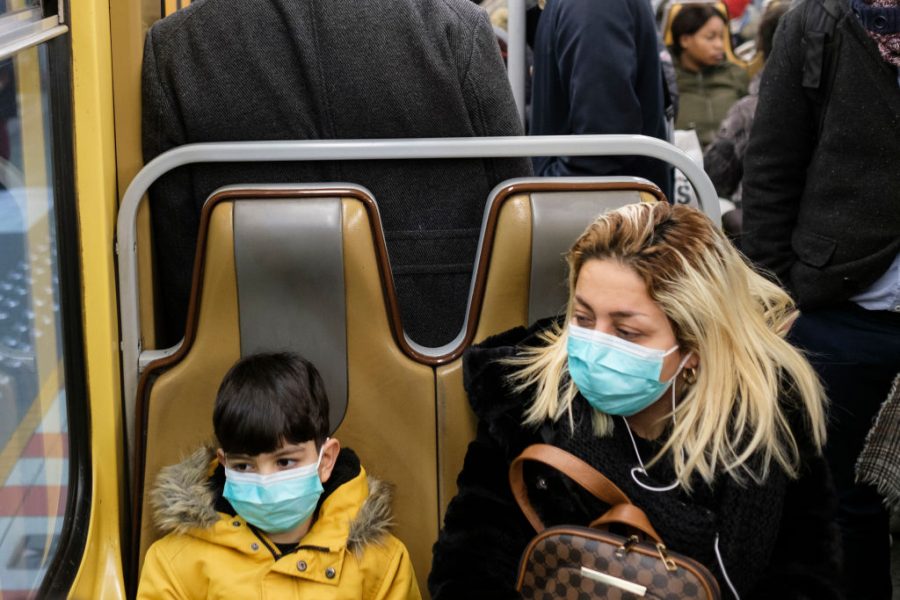 A mother and son wear masks while sitting in a bus.
