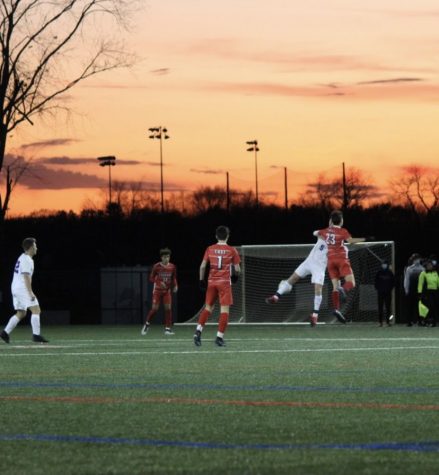 Sophomore Evan Pfeiffenberger rises for a header as the sun sets behind the turf fields at Decou Sports Complex. 