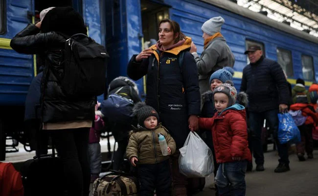 Ukrainians flee their home with children and belongings.