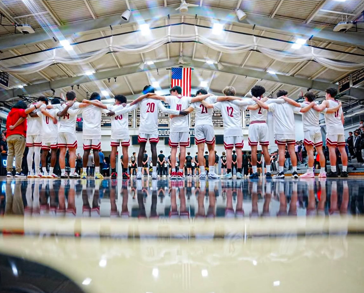 East Varsity Boys Basketball team stands together before the game starts.