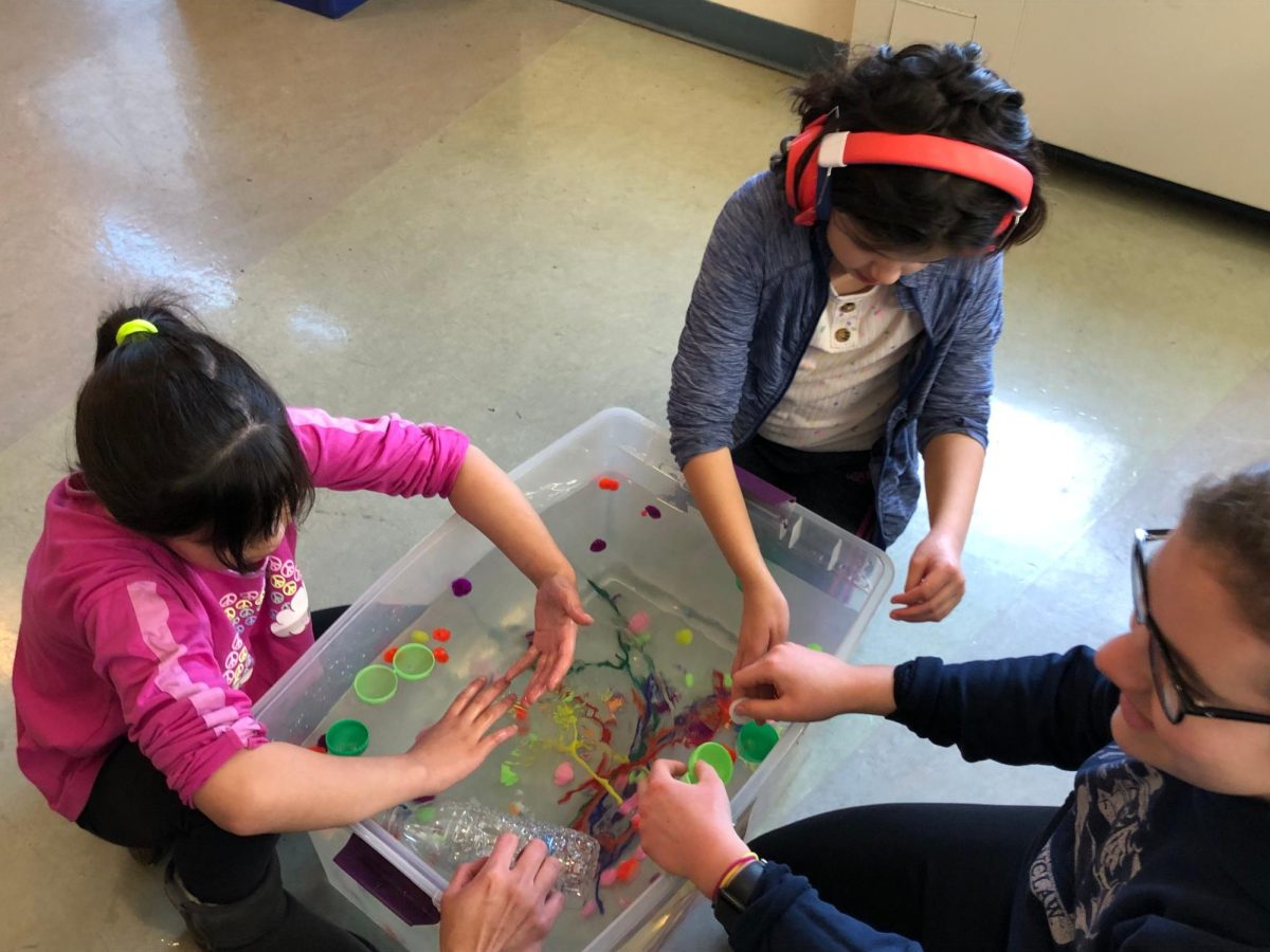 Students enjoy playing with a DIY sensory water tub at an AAC outreach event. 