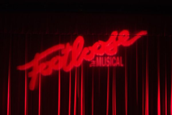 Before the show, "Footloose the Musical" is projected on the closed curtains.