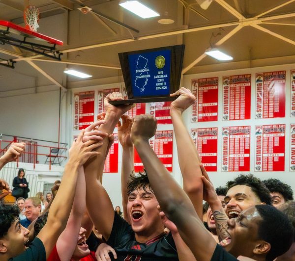 Noahm Marciano (21) hoists the Sectional Champions trophy with teammates surrounding him after the hard-fought game.