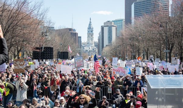 No Kings protesters gather at the rally at the intersection of the Benjamin Franklin Parkway and 22nd street, with Philadelphia City Hall in the background.  