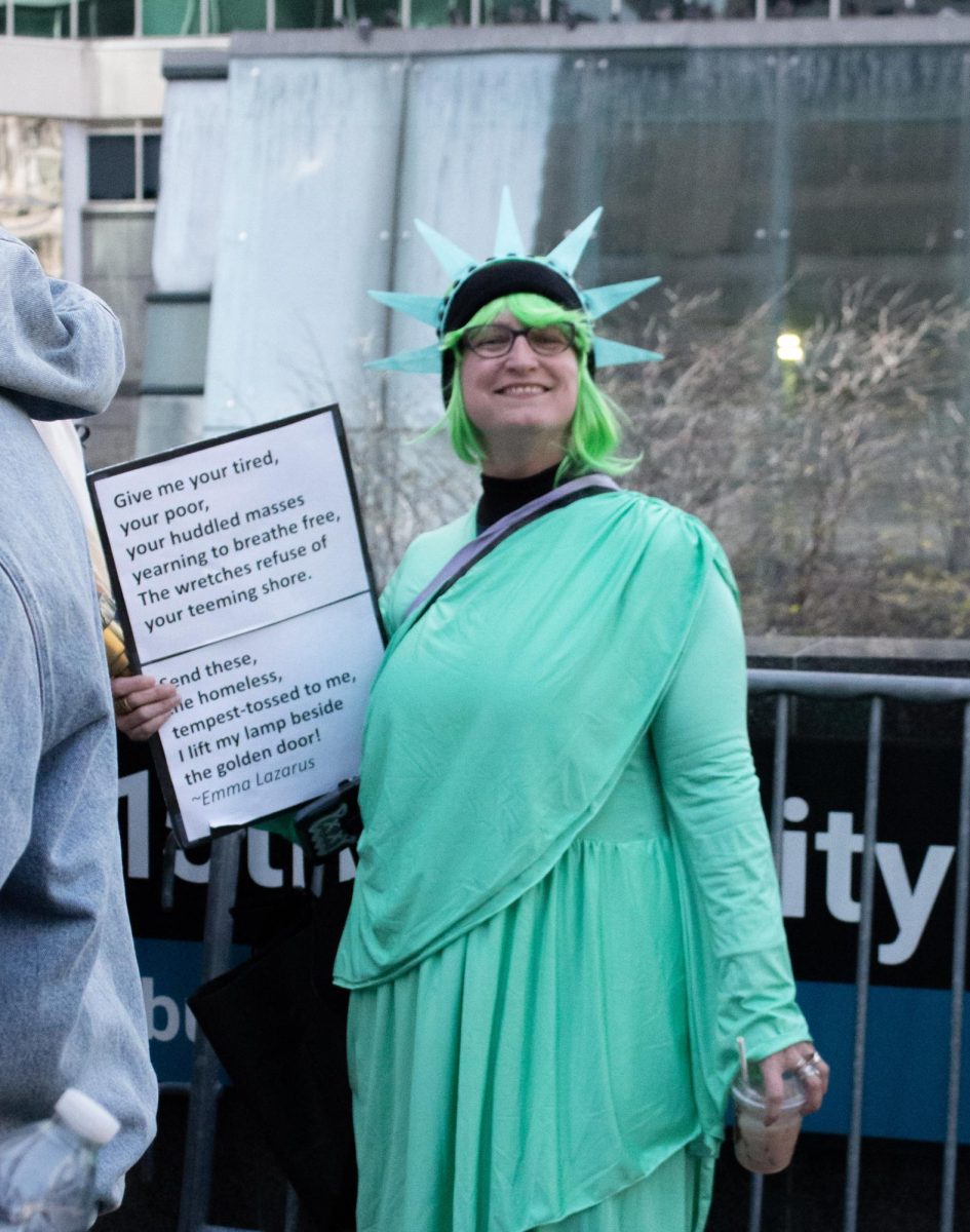 A protester dressed as the Statue of Liberty carries a poem by Emma Lazarus.
