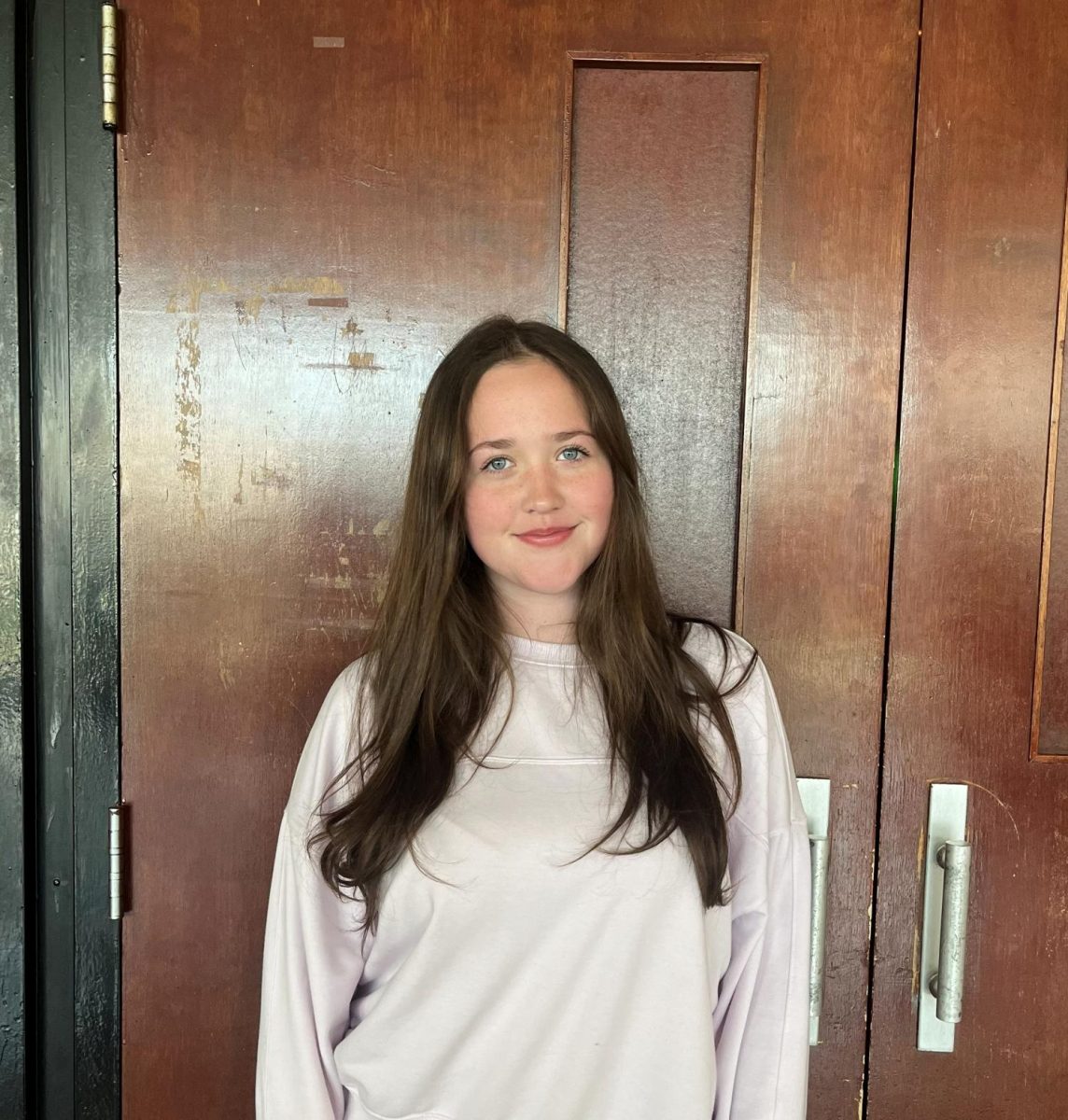 Alexis Nowakowski ('26) poses in front of the auditorium doors. 
