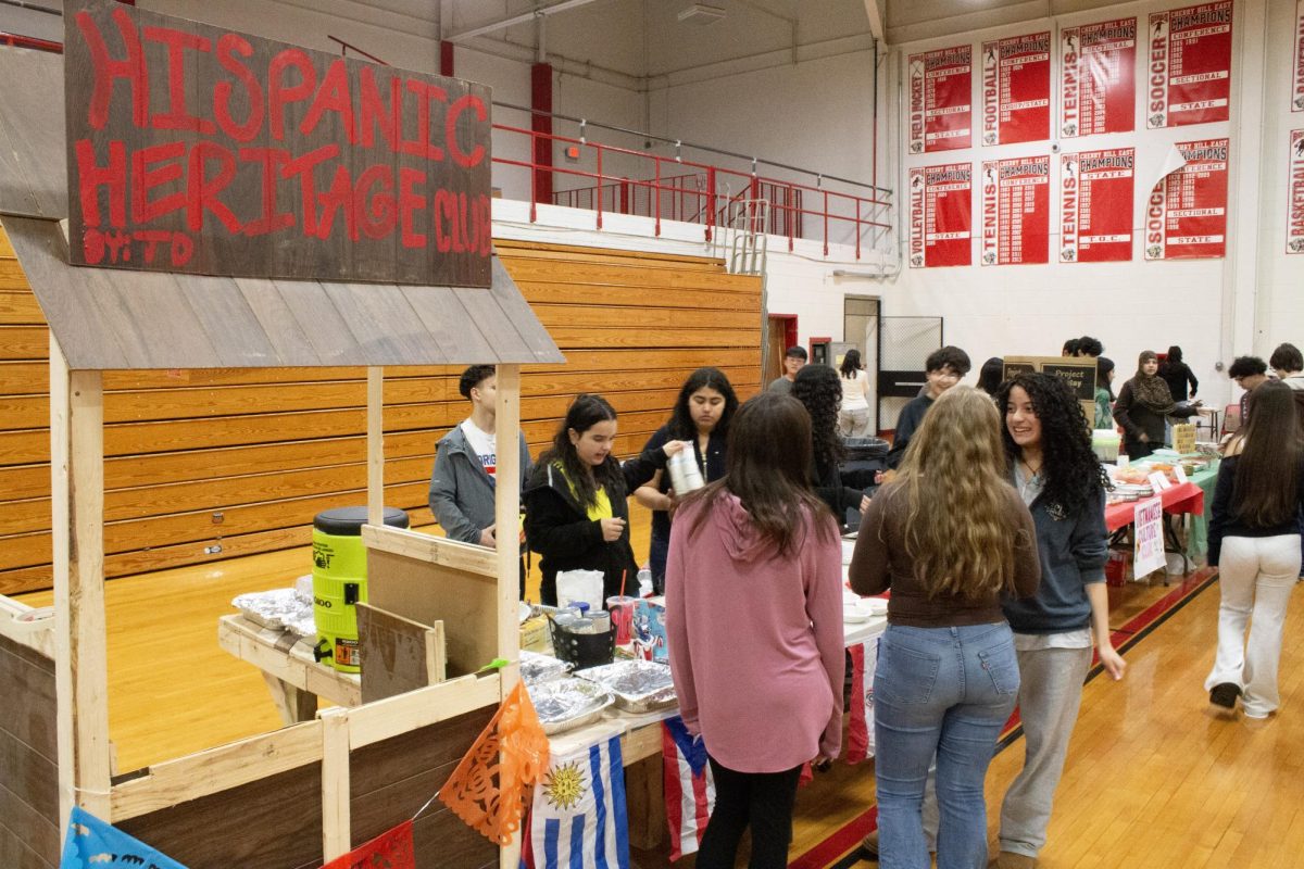 The Hispanic Heritage Club features a wooden stand draped with papel picado at their booth.