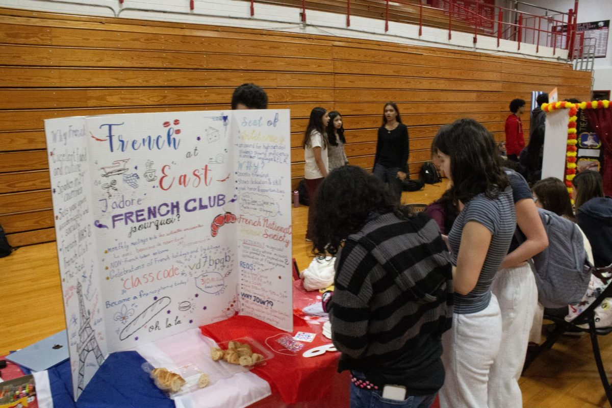 The French Club offers croissants at their booth, along with a mask decorating station with rhinestone stickers.