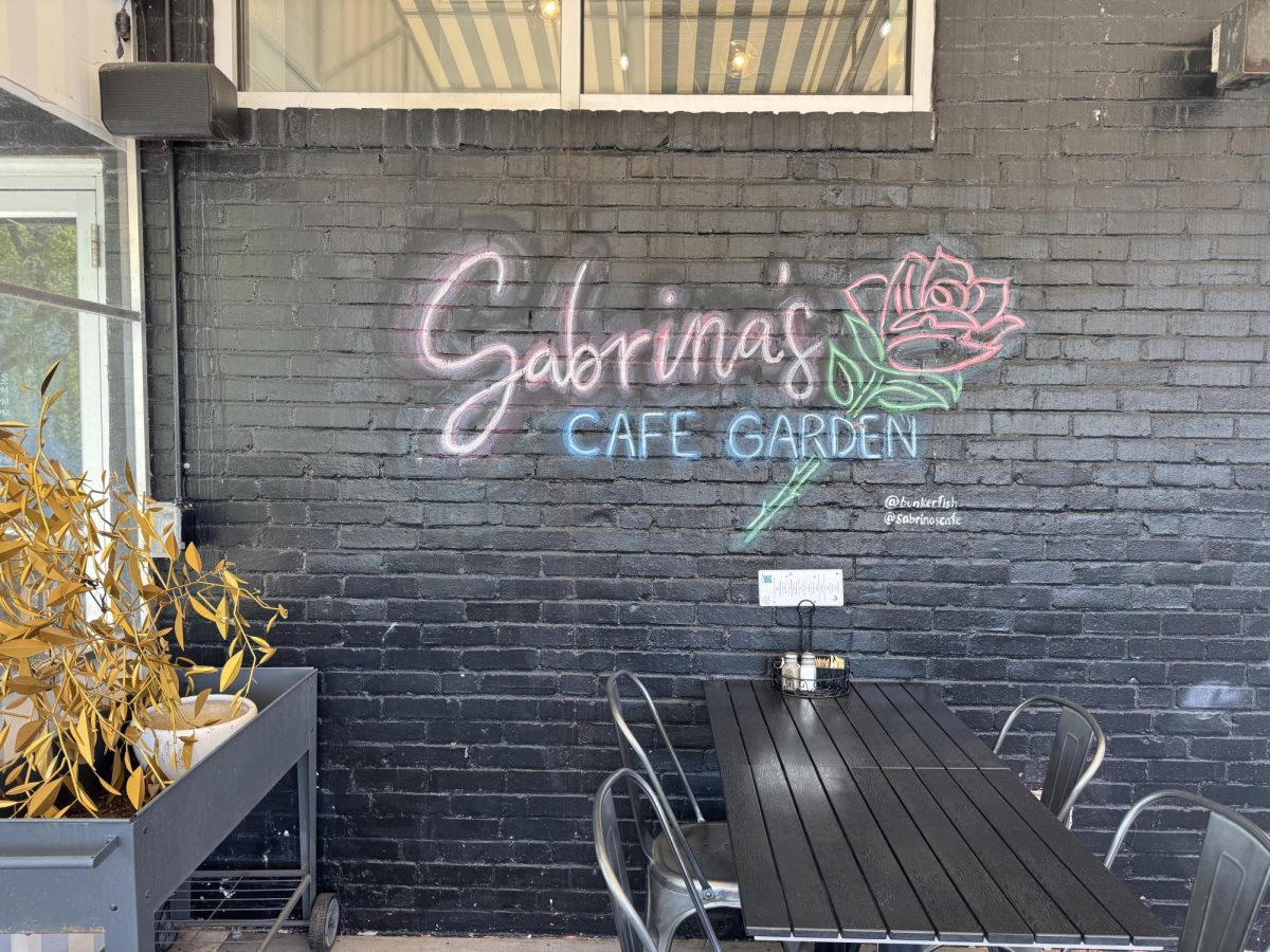 A wall on the patio is painted with a decorative logo of Sabrina's Cafe with a rose